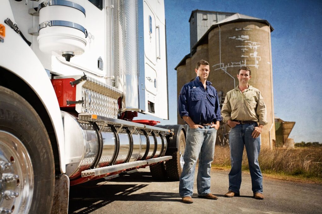Gordon and Phil Moss standing next to truck in front of grain silos